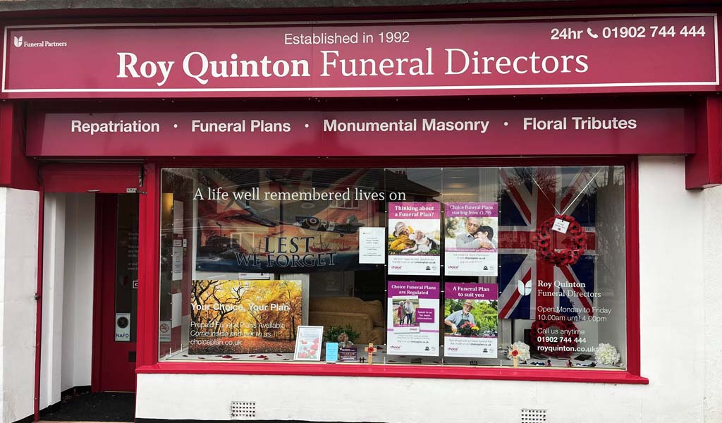 Roy Quinton Funeral Directors Tettenhall Wood branch decorated a Remembrance Day window display. There is a flag with 'lest we forget' on it, a union jack and a poppy wreath in the window.